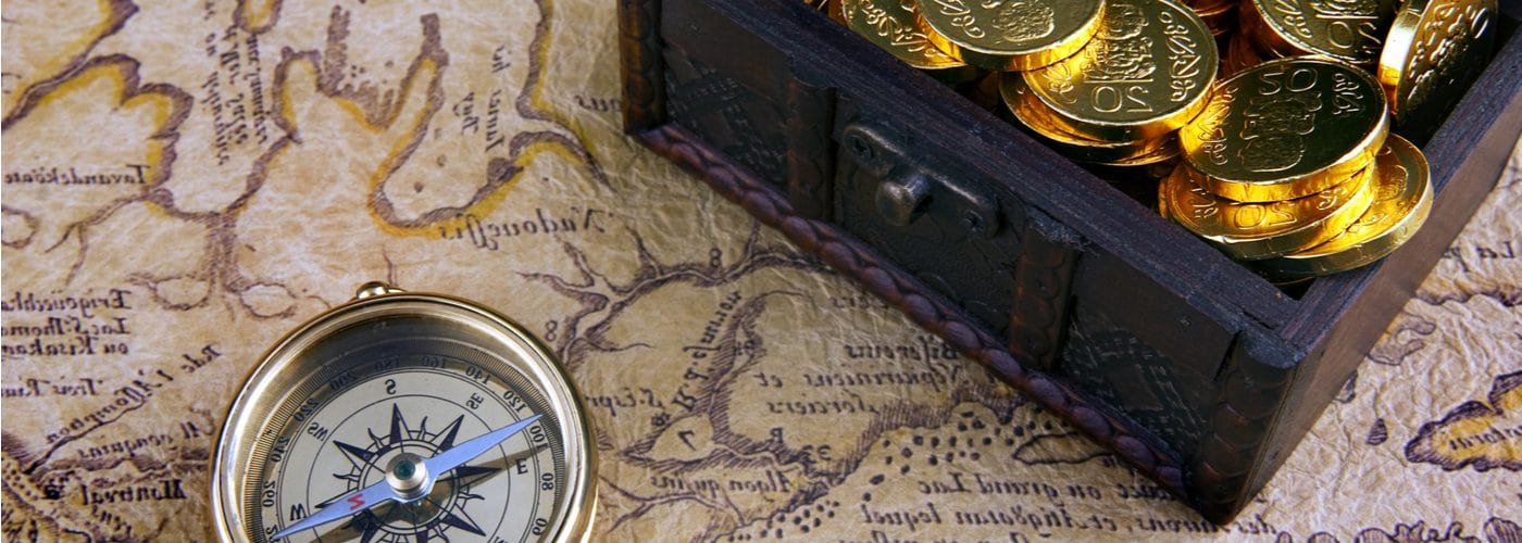 compass and box of gold coins on top of map